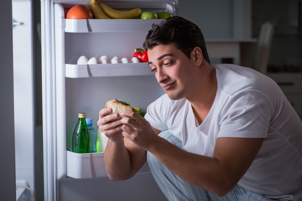 A man looking at a food in front of an open fridge