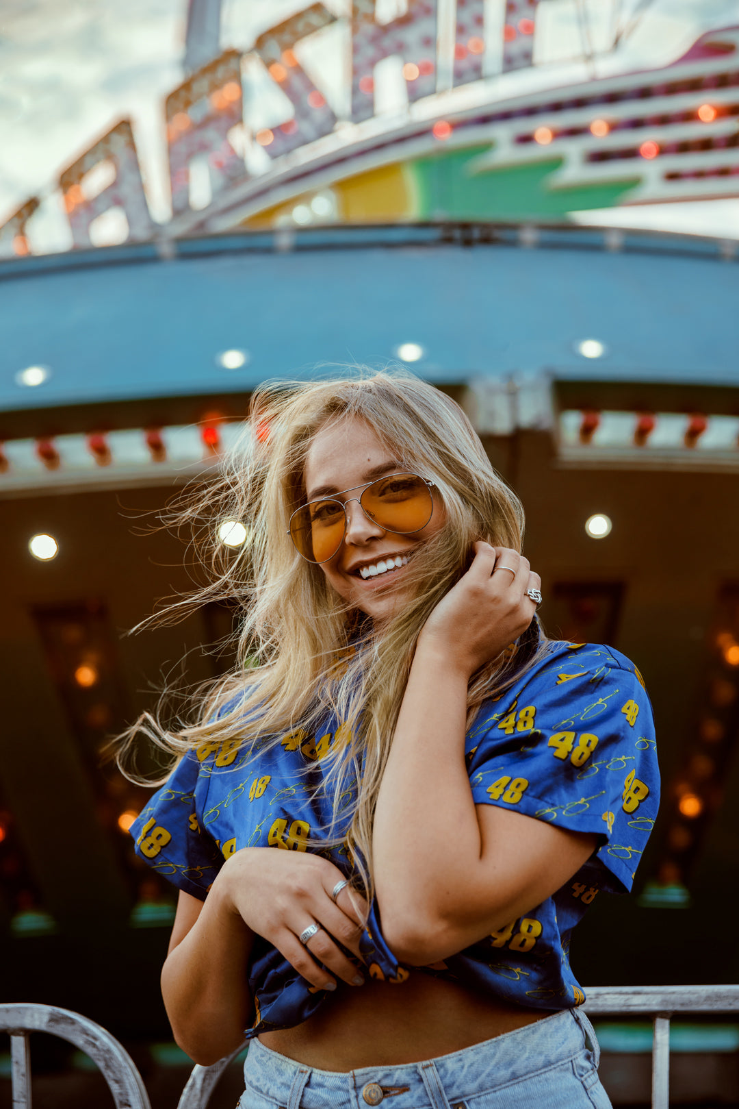 A happy woman smiling and wearing sunglasses at a fairground